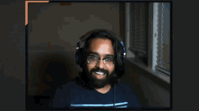 a man with a beard wearing headphones and glasses is raising his arms