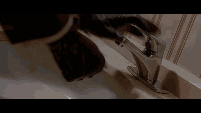 a close up of a person washing their hands in a bathroom sink