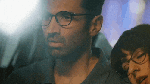 a man wearing glasses is sitting next to a woman wearing glasses
