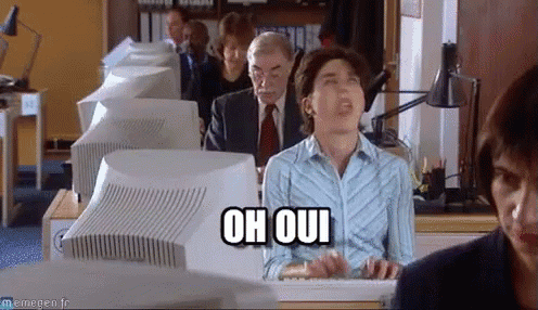 a woman sitting in front of a computer with the words oh oui on her shirt