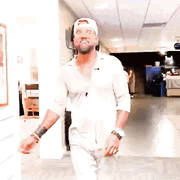 a man in a white shirt and hat is walking down a hallway