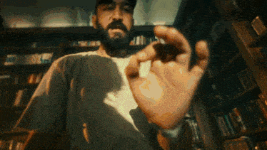 a man with a beard holds something in his hand in a library