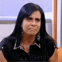 a woman with long black hair is making a sad face while wearing a black shirt .