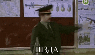 a man in a military uniform is standing in front of a bulletin board with posters on it .