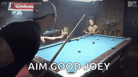 a man is playing pool in a bar and a woman is sitting at a table .