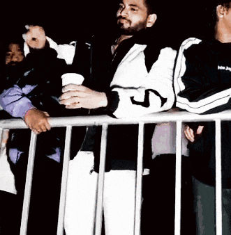 a man wearing a jacket with the letter j on it stands behind a fence