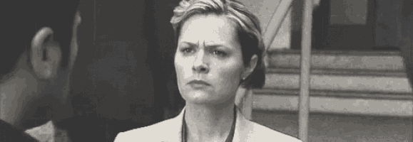 a black and white photo of a woman in a suit making a funny face .