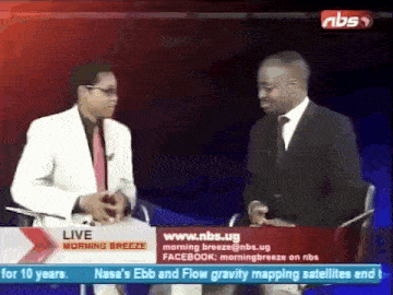 two men are sitting in front of a sign that says ' live morning breeze ' on it