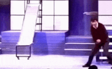 a man is dancing on a stage with a slide in the background