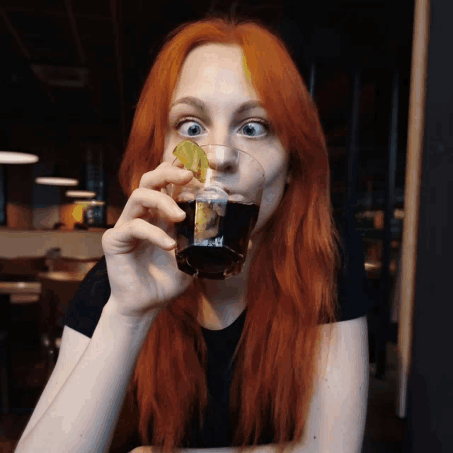 a woman with red hair is drinking from a glass