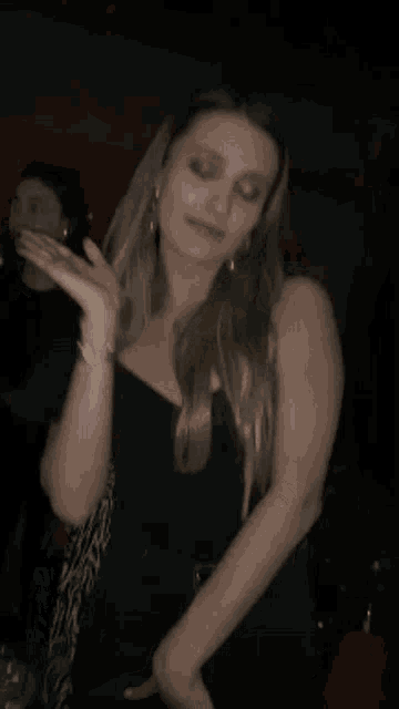 a woman is dancing in a dark room with her hair blowing in the wind