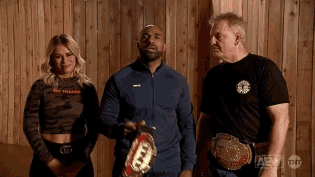 a man is holding a wrestling belt while standing next to two other people