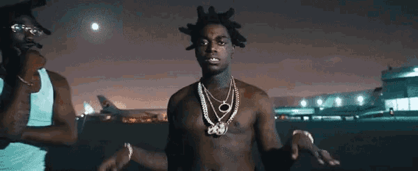 a man without a shirt is wearing a necklace with the letter o on it .