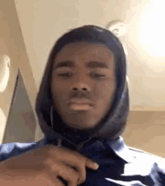 a man wearing a hooded jacket and a blue shirt is making a funny face .