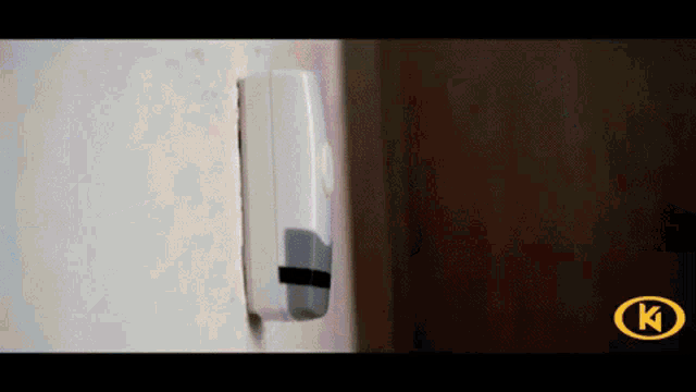 a remote control is attached to a wall with a k on the bottom right
