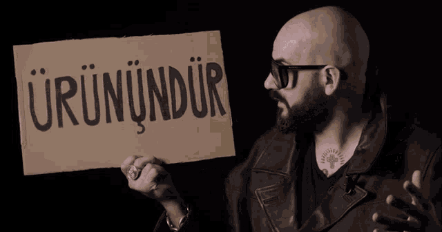 a bald man holding a cardboard sign that says urunudur