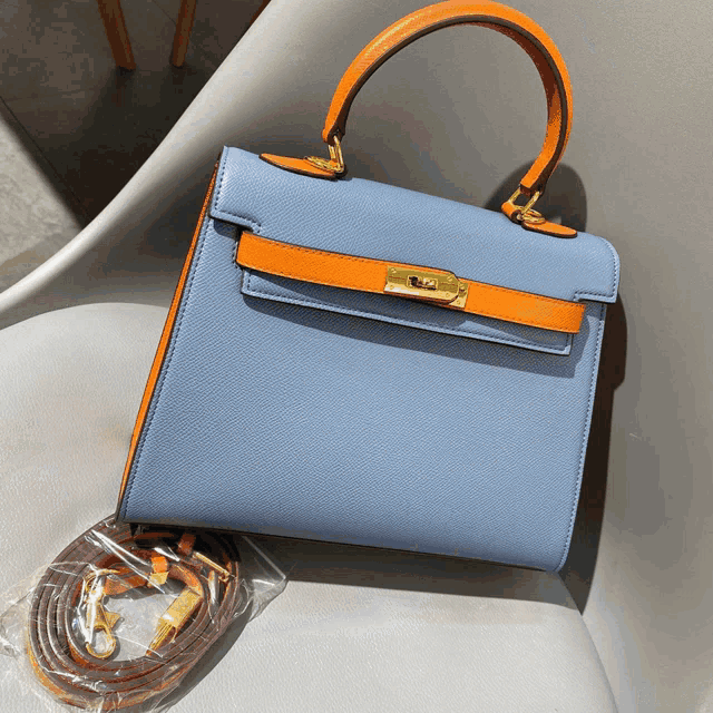 a blue and orange purse with a brown strap is sitting on a chair