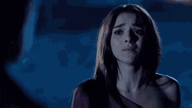 a woman in a purple one shoulder top is crying in the dark
