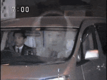 a man is driving a car with the time of 7:00