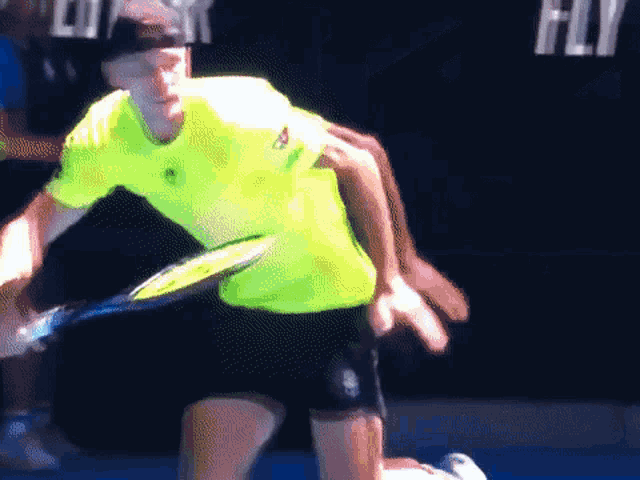 a man in a yellow shirt is holding a tennis racket
