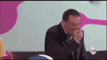 a man in a suit and tie is sitting at a table with his hand on his chin .