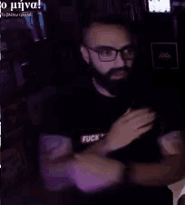 a man with glasses and a beard wearing a black shirt that says fuck