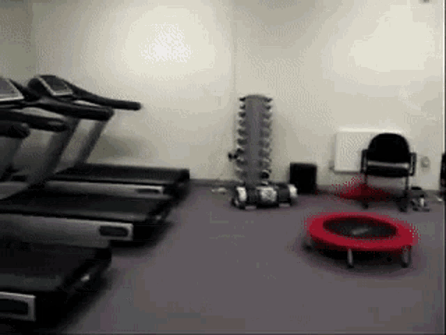 a gym with treadmills a trampoline and a chair