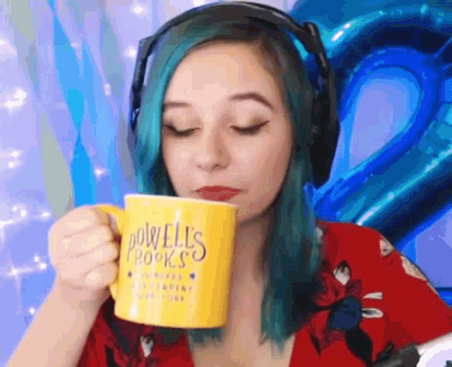 a woman with blue hair is wearing headphones and holding a yellow mug .