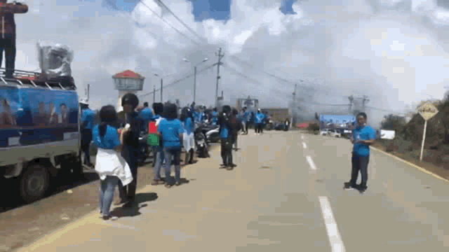 a group of people are standing on the side of a road in front of a sign that says ' atencion '