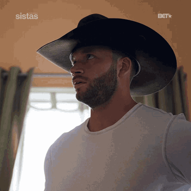 a man wearing a cowboy hat with the word sistas on the bottom