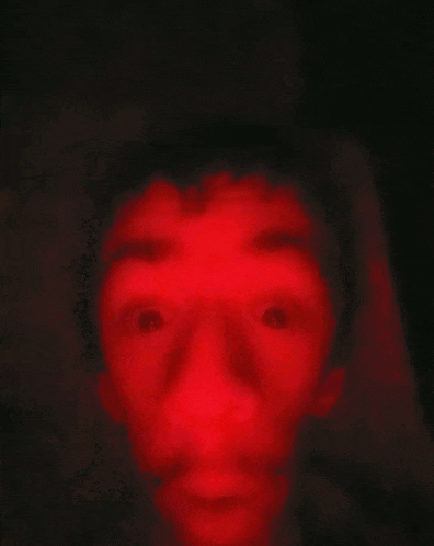 a close up of a person 's face with a red light behind it .