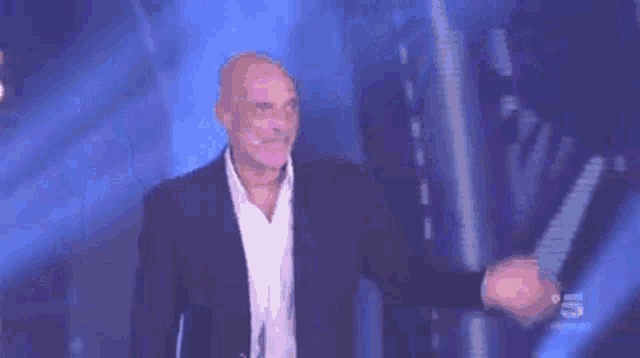 a man in a suit and white shirt is dancing on a stage with the number 5 on the bottom