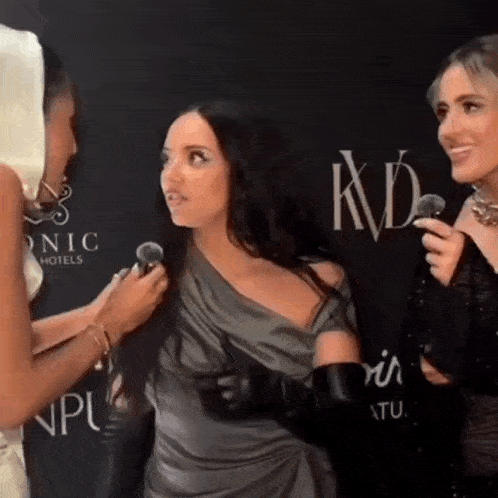 a woman in a gray dress is being interviewed by a woman in a black dress .