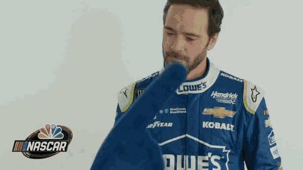 a man in a blue and white racing suit is holding a blue shirt .