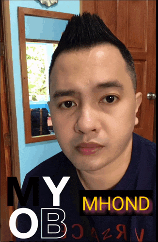 a man with a mohawk stands in front of a mirror and a sign that says my mhond on it