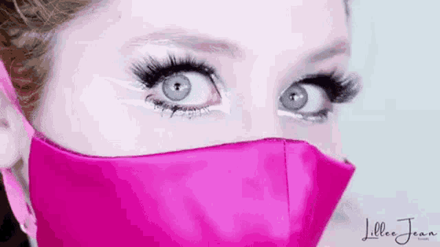 a close up of a woman 's face wearing a pink mask and makeup .