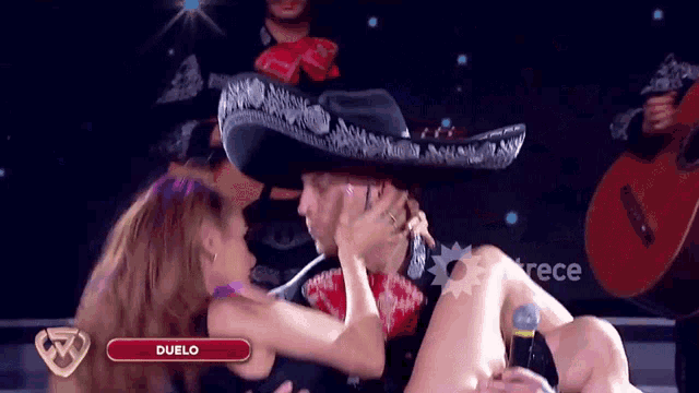 a man in a sombrero is kissing a woman in front of a sign that says duelo on it