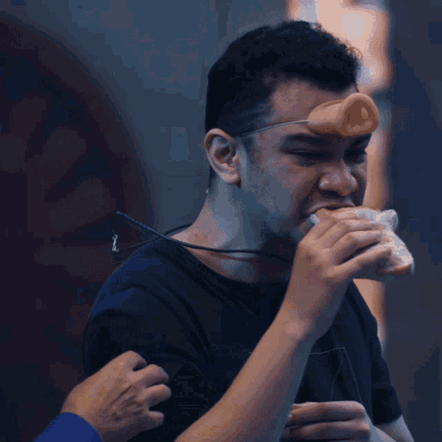 a man with a pig nose on his head is eating a sandwich
