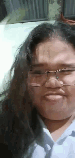 a girl wearing glasses is making a funny face .