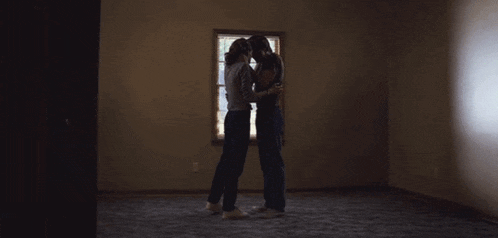 two people are hugging each other in an empty room .