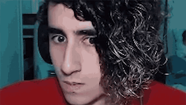 a close up of a man with curly hair wearing headphones .