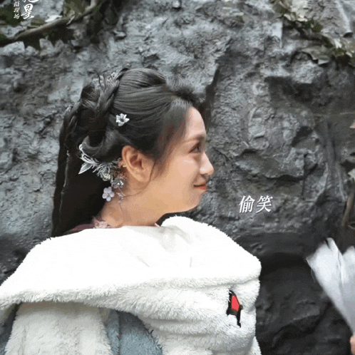 a woman wearing a white jacket with chinese writing on the back is smiling