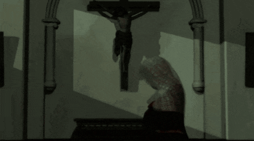 a woman is standing in front of a cross in a dark room