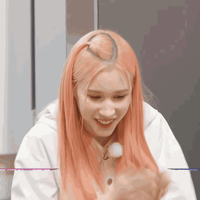 a woman with pink hair is smiling and holding a marshmallow in her hand