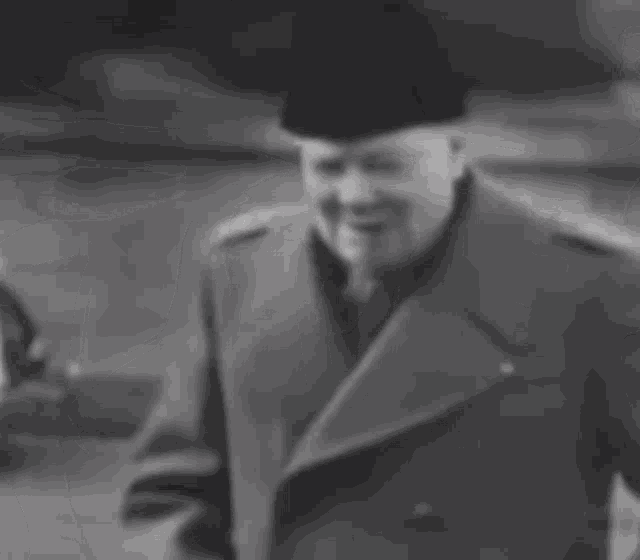 a black and white photo of a man wearing a hat and coat .