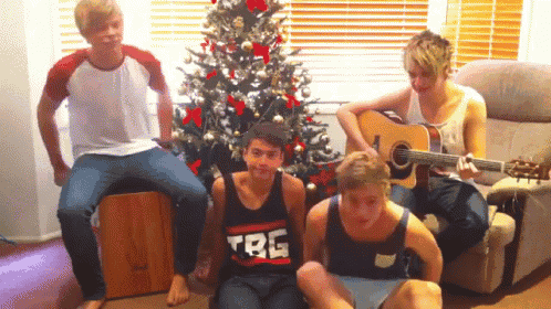 a group of young men are posing for a picture in front of a christmas tree