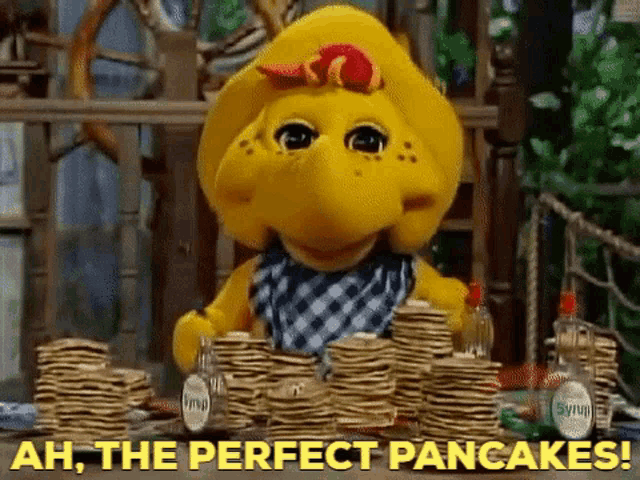 a stuffed animal sitting at a table with a stack of pancakes and the words ah the perfect pancakes .
