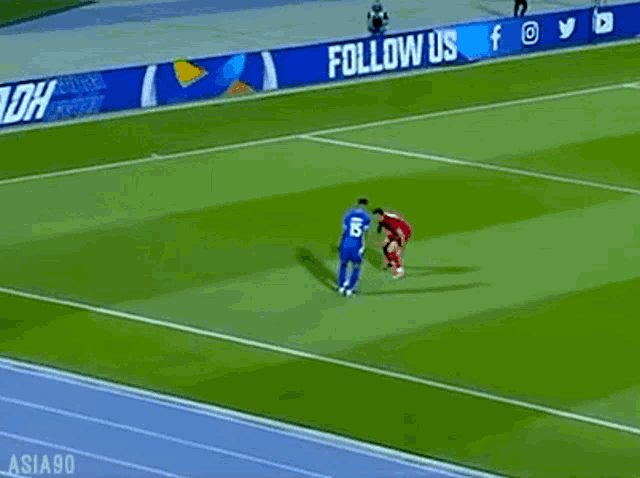 two soccer players on a field with a follow us sign behind them