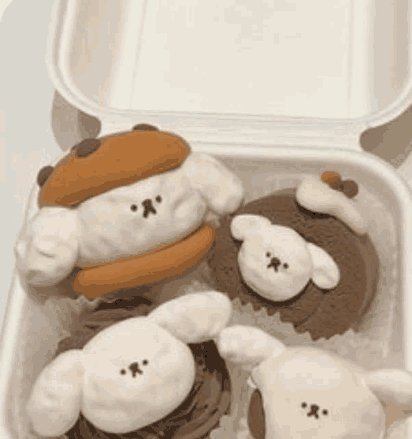 a styrofoam container filled with cupcakes decorated to look like animals .