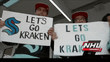 a couple of people holding signs that say lets go kraken
